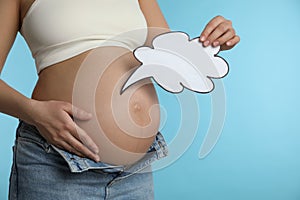 Pregnant woman with empty paper thought cloud on blue background, closeup. Choosing baby name