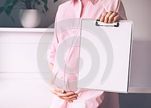 Pregnant woman with empty white paper as medical card, agreement blank. Template for text