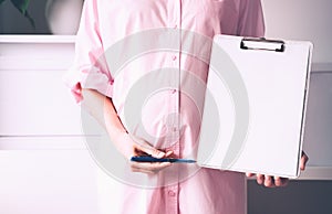 Pregnant woman with empty white paper as medical card, agreement blank. Template for text