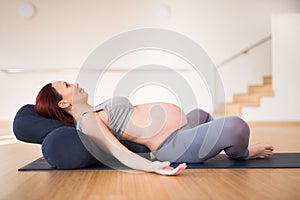 Pregnant woman is engaged in yoga. Reclined Bound Angle Pose or Supta Baddha Konasana