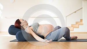 Pregnant woman is engaged in yoga. Reclined Bound Angle Pose or Supta Baddha Konasana