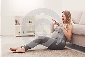 Pregnant woman enjoying of eating chocolate bar