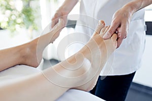 Pregnant woman enjoying reflexology foot massage in wellness spa