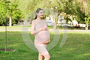 Pregnant woman enjoying and relaxing outside in the park. Pregnancy, maternity and happiness