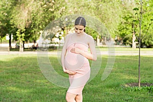 Pregnant woman enjoying and relaxing outside in the park. Pregnancy, maternity and happiness