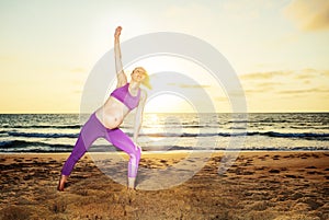 Pregnant woman exercise stretching on sunset beach