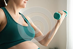 Pregnant woman is exercising with dumbbells. Healthy lifestyle during pregnancy. Sports activities