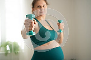 Pregnant woman is exercising with dumbbells. Healthy lifestyle during pregnancy. Sports activities