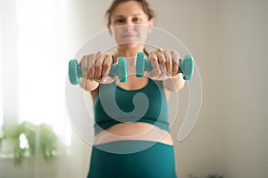 Pregnant woman is exercising with dumbbells. Healthy lifestyle during pregnancy. Sports activities