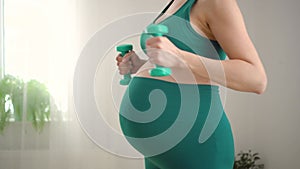 Pregnant woman is exercising with dumbbells. Healthy lifestyle during pregnancy. Sports activities