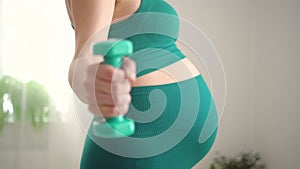 Pregnant woman is exercising with dumbbells. Healthy lifestyle during pregnancy. Sports activities