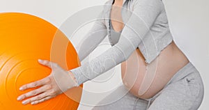 Pregnant woman exercising with fit ball making squats