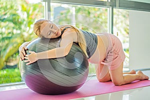 Pregnant woman exercising on fitball at home. Pregnant woman doing relax exercises with a fitness pilates ball. Against