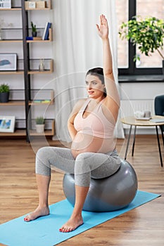 Pregnant woman exercising on fitness ball at home