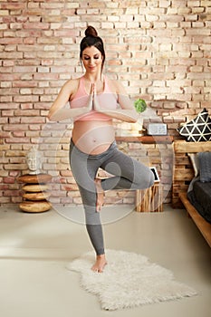 Pregnant woman exercising at home in yoga pose