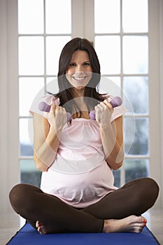 Pregnant Woman Exercising With Weights At Home