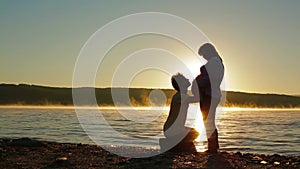 A Pregnant Woman And Expectant Father On Lake Silhouette.