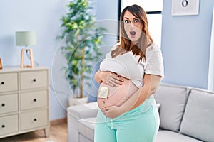 Pregnant woman expecting a baby wondering sex afraid and shocked with surprise and amazed expression, fear and excited face