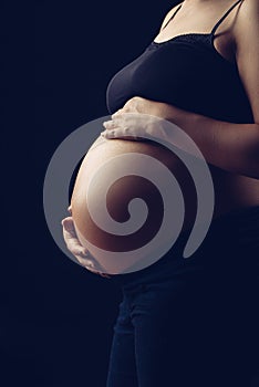 Pregnant woman exposing her belly in beutiful light.