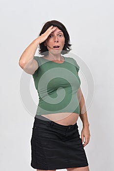 Pregnant woman with expression of forgetting on white background