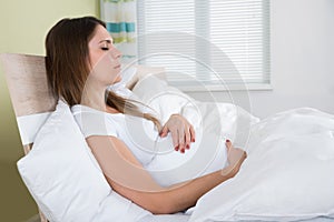 Pregnant Woman With Eyes Closed On Bed