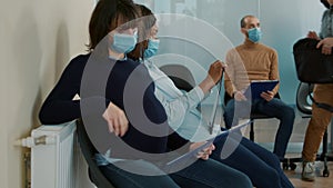 Pregnant woman with face mask sitting in waiting queue