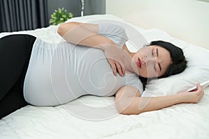 Pregnant woman feeling nauseous on bed