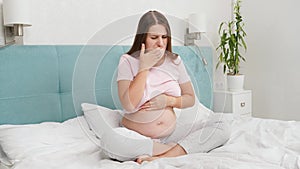 Pregnant woman feeling sick with nausea sitting on bed at morning. Intoxication during pregnancy