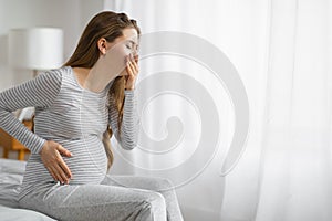 Pregnant woman feeling unwell on bed