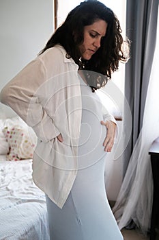 A pregnant woman feels pain and tension in her back Big belly and the difficulty