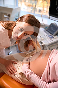 Pregnant woman with female doctor examining and listening baby& x27;s heartbeat