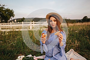 Pregnant woman in the field eating fresh backed crispy croissant. Healthy food. Young woman eats very appetizing