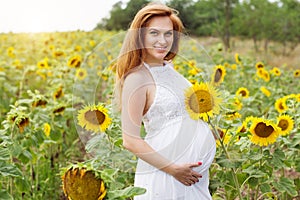 Pregnant woman in the field with sunflowers