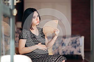 Pregnant Woman Fighting Hot Flushes with a Fan