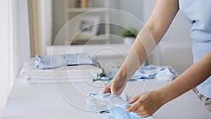 Pregnant woman folding baby boys clothes at home 5