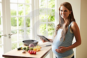 Pregnant Woman Following Recipe On Digital Tablet