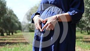Pregnant woman forming heart sign on belly
