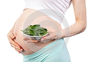 Pregnant woman with fresh green spinach, healthy nutrition containing iron during pregnancy