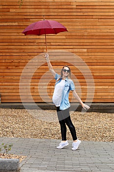 Pregnant woman in full height holds an umbrella