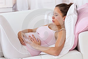 Pregnant woman getting a contraction at home in the living room photo