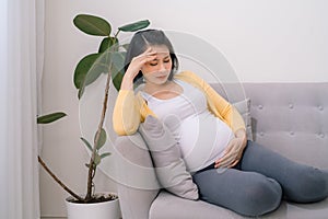 Pregnant woman getting a contraction in the living room at house