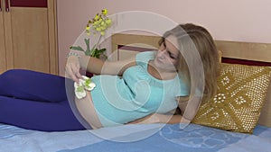 Pregnant woman girl play with baby shoes on round stomach