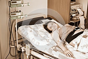 A pregnant woman gives birth in a hospital with a drip and a CTG machine. A woman on a clinic bed during labor pains