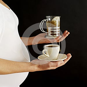 Pregnant woman with a glass of tea and a cup of coffee. Conceptual image shot