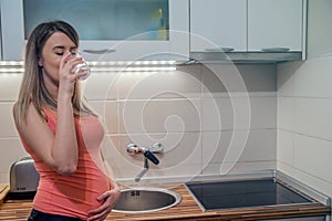 Pregnant woman with glass of water in hand, concept of healthy l