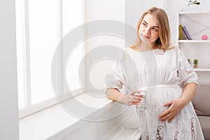 Pregnant woman with glass of water sitting on sofa