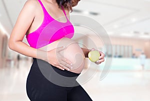 Pregnant woman with green apple in hospital