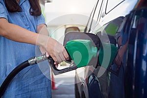 Pregnant woman hand pumping gasoline fuel in car at gas station