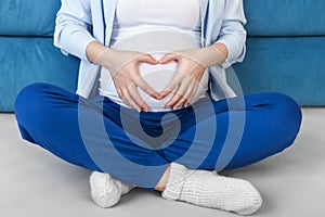 Pregnant woman with hands in heart shape on belly