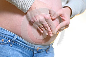 Pregnant woman hands making heart shape on belly.